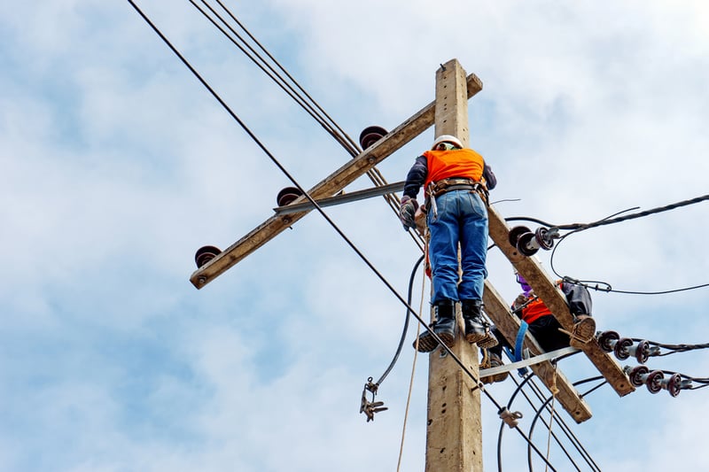 An electrical worker high up repairing some power lines